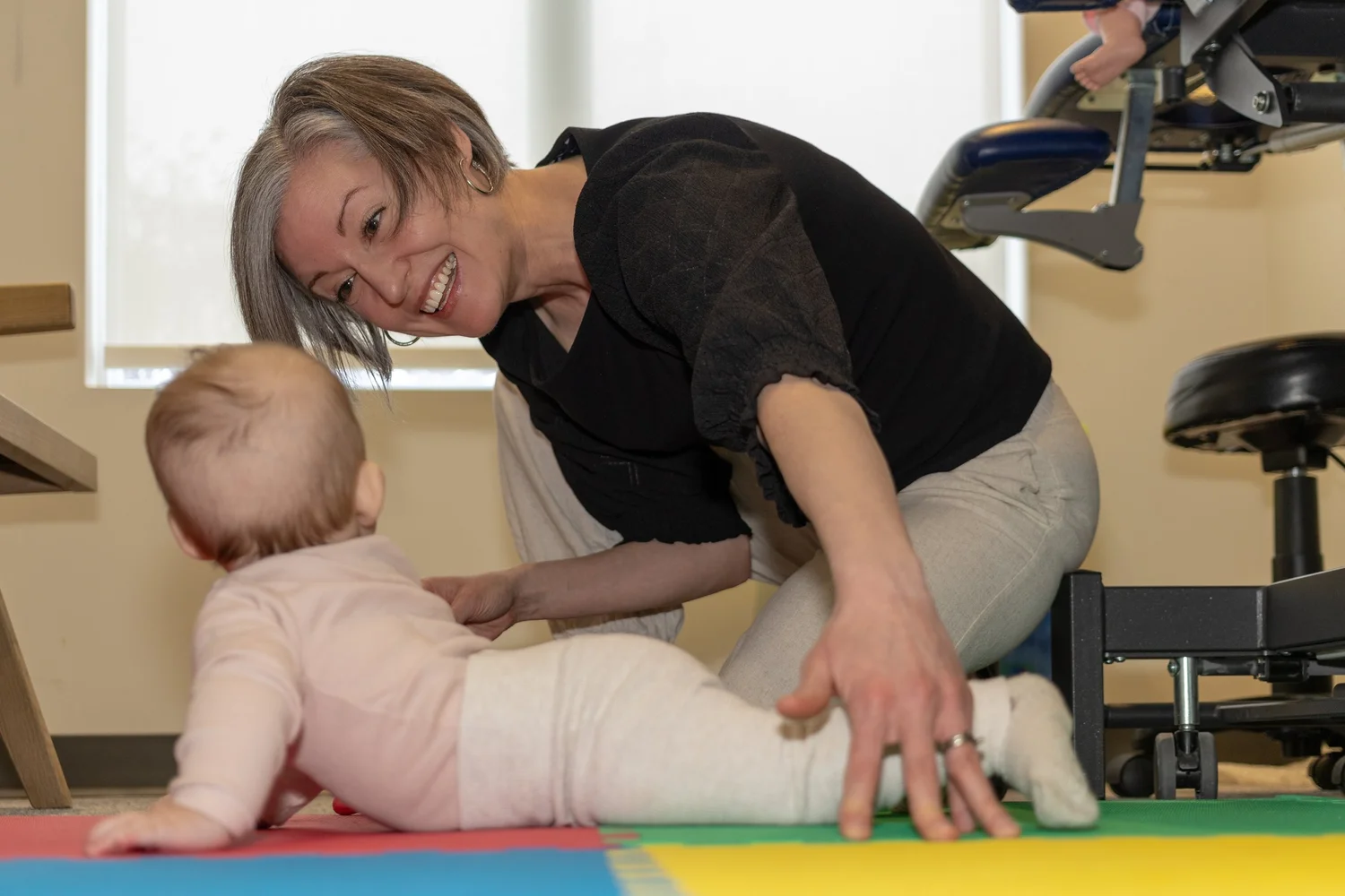 Physiotherapist supporting an infant during floor-based movement