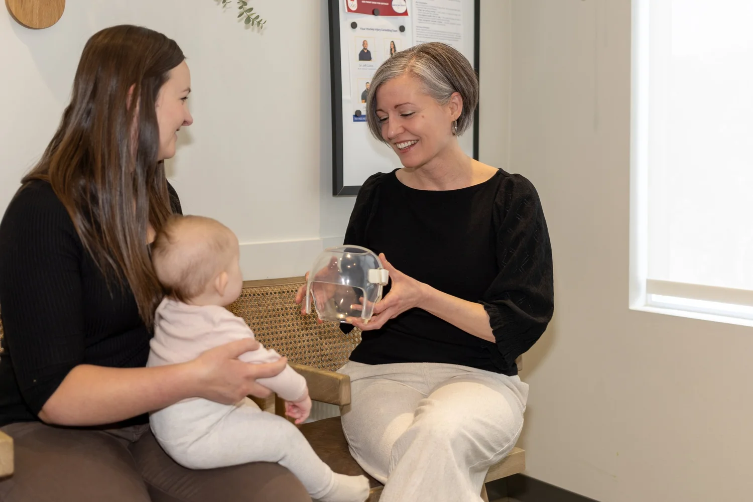Physiotherapist discussing infant head shape with a parent holding a baby