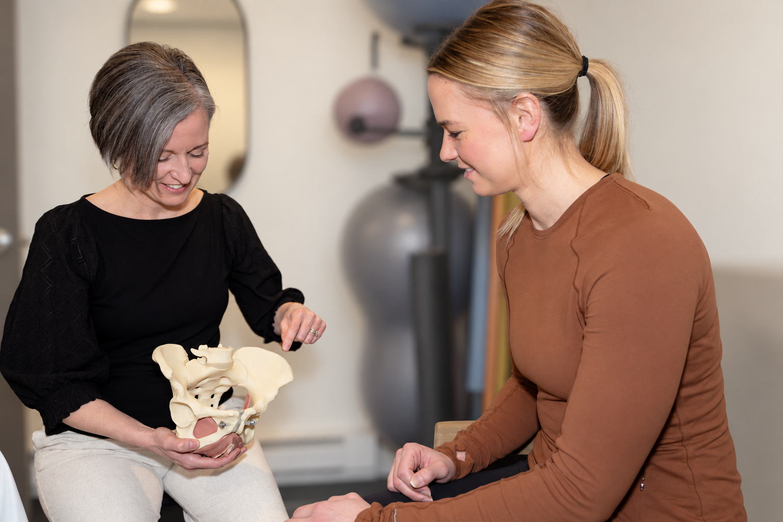 Physiotherapist explaining a pelvic model during a patient conversation