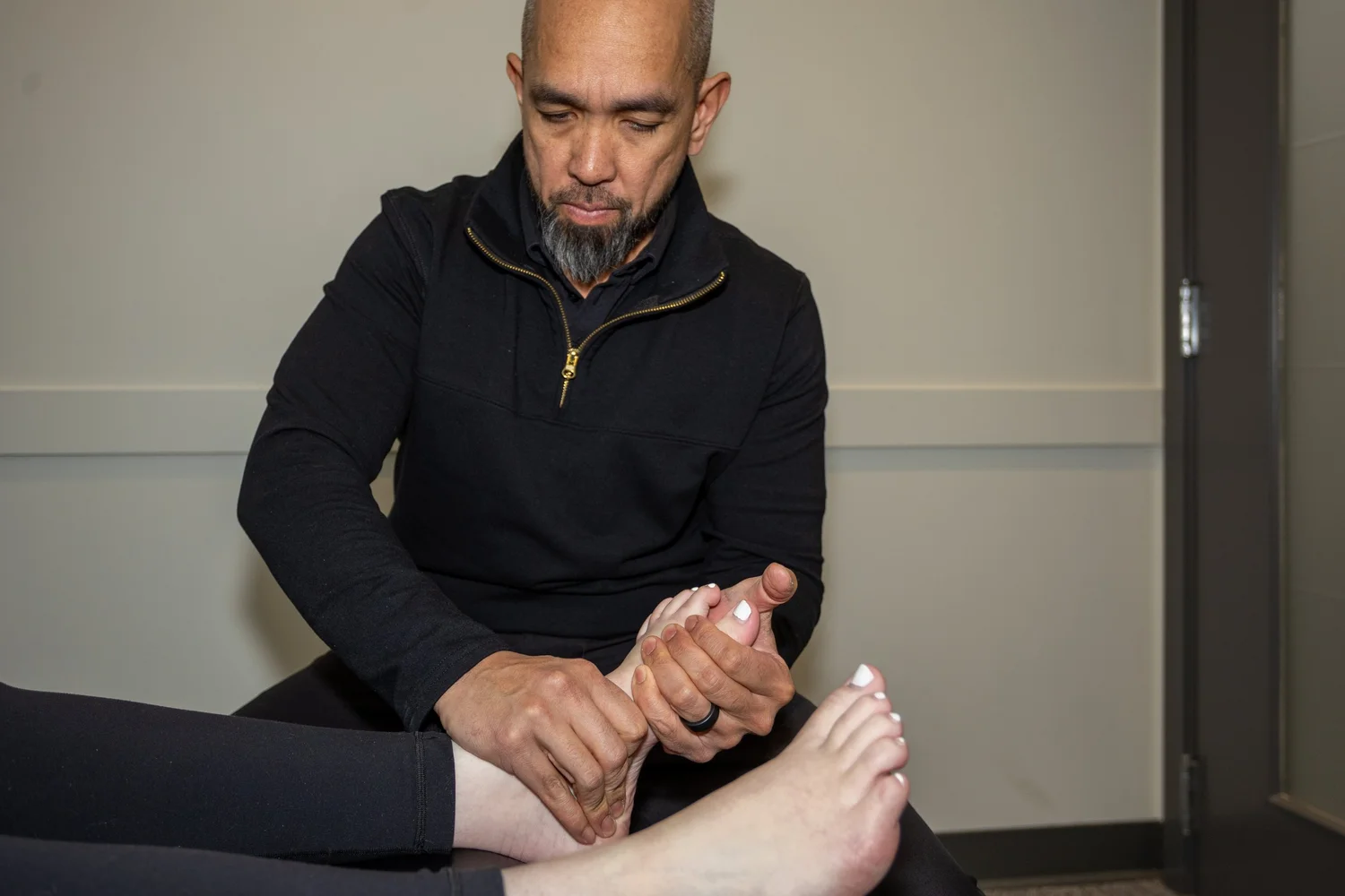 Sport chiropractor examining a patient's foot and ankle