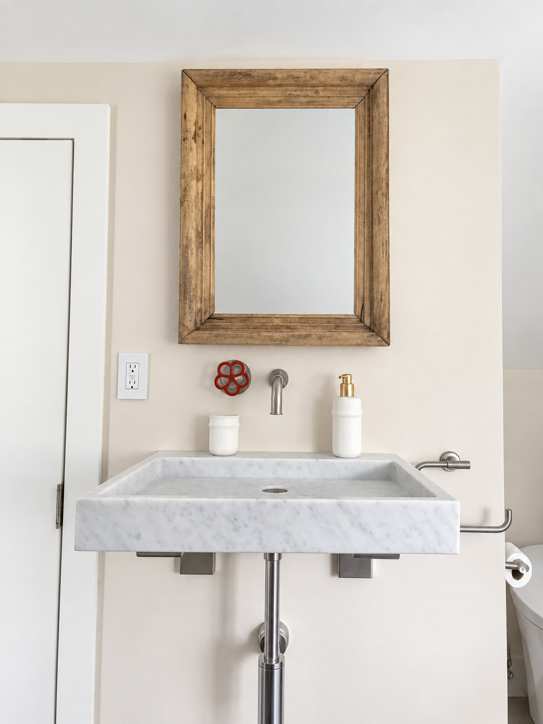 Marble bathroom sink with wall-mounted faucet, rustic wood mirror, and exposed chrome drain