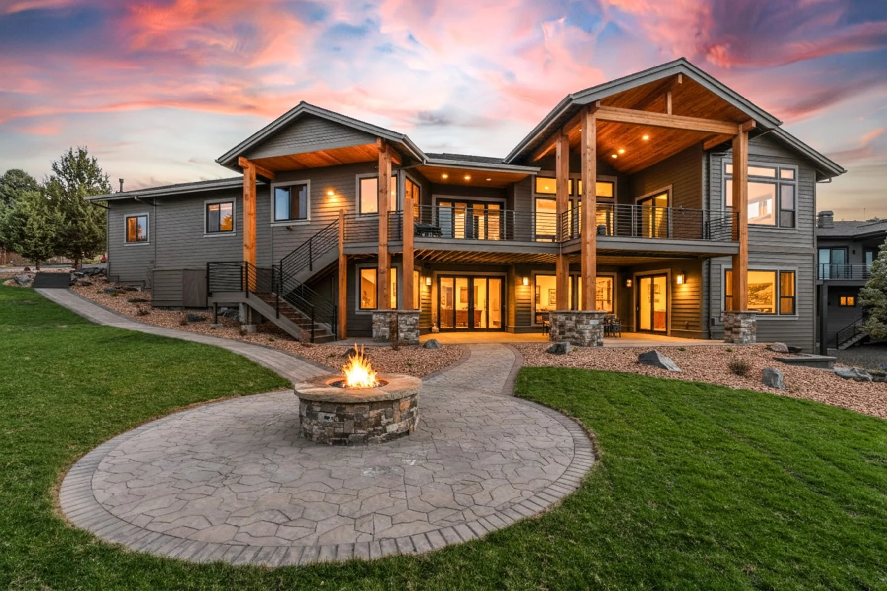 View Point, a two-story custom home in Redmond at sunset with covered timber decks and a stone fire pit
