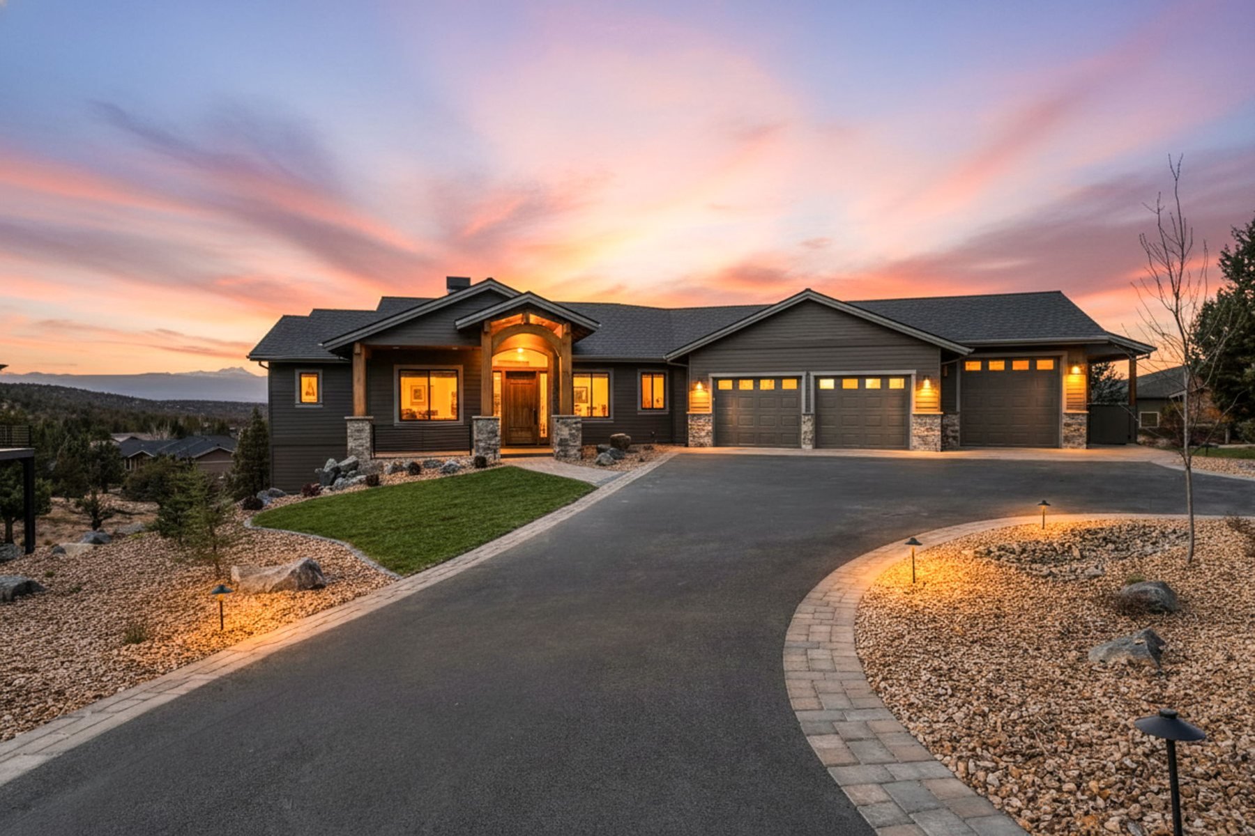 Custom single-level home in Redmond, Oregon at sunset, with a timber-framed entry, three-car garage and Cascade mountain views