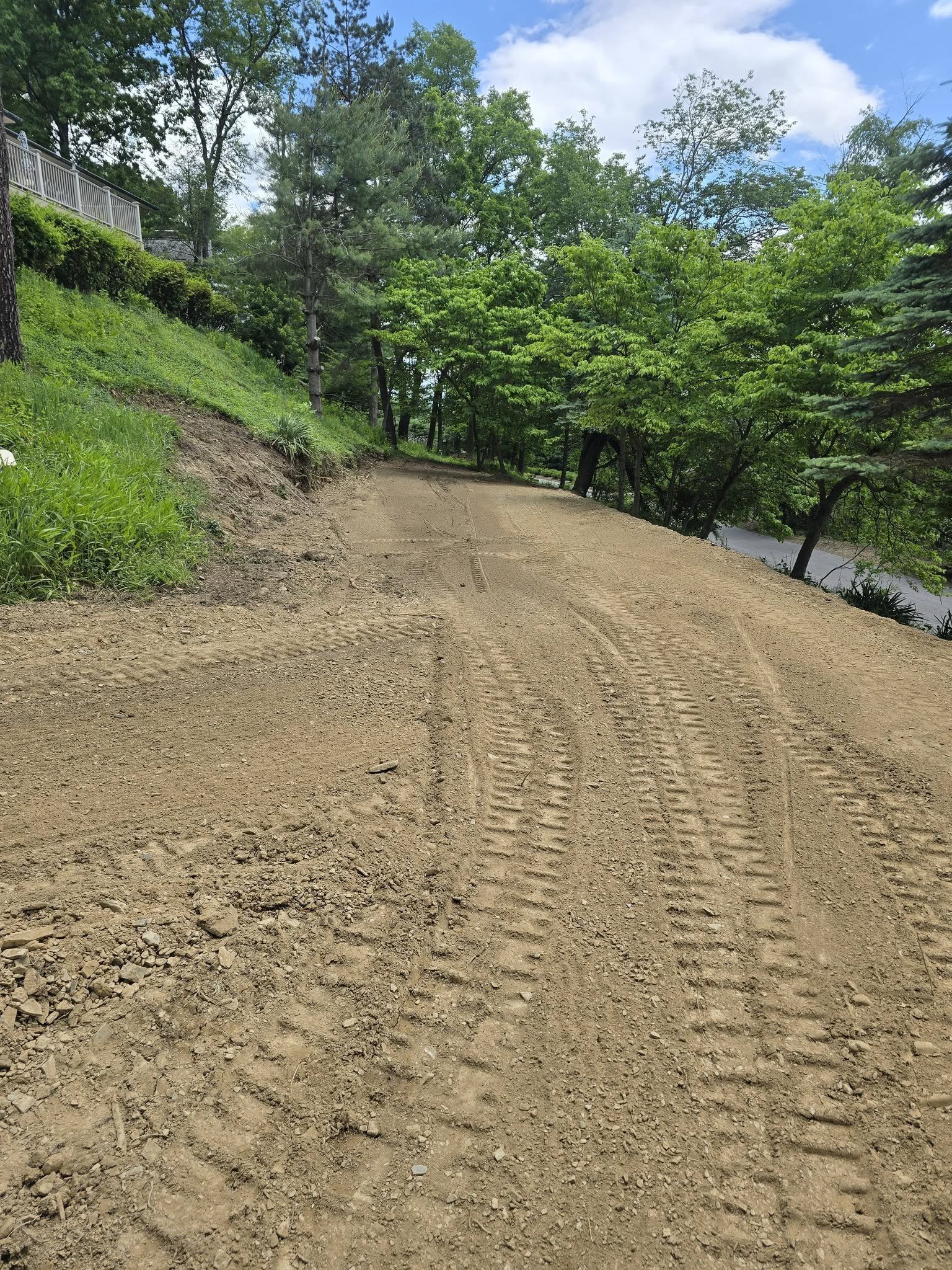 Broad cleared and graded area beside the wooded slope