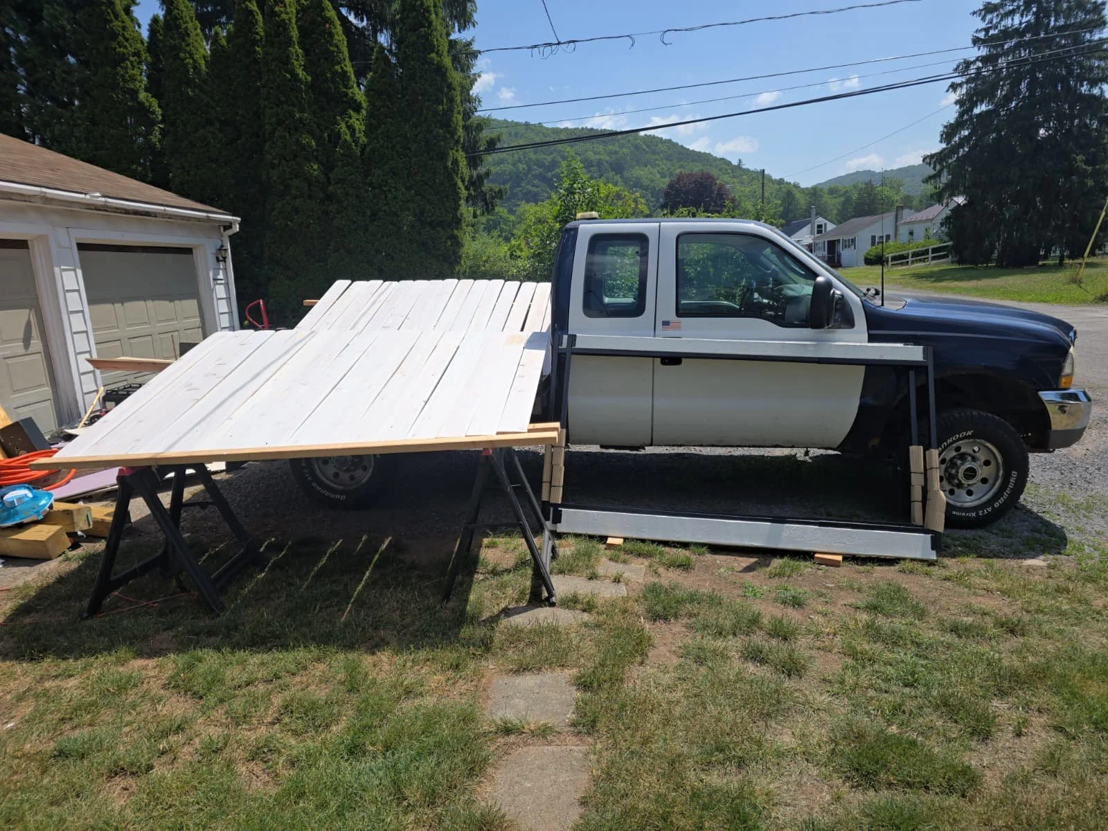 Cedar planks painted white on sawhorses beside the gate frame