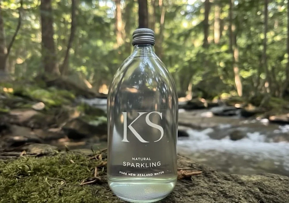 KS bottle in forest by clear running water