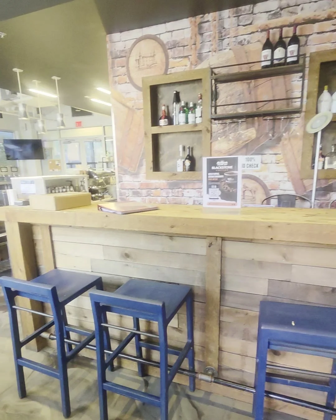 Reclaimed wood bar with navy stools and a brick wall