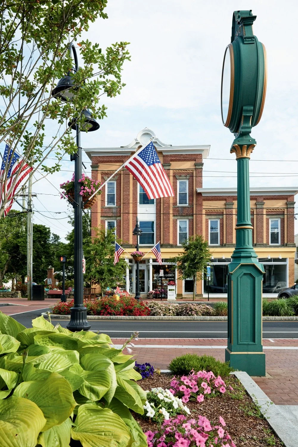 Downtown Madison with American flags along the street and a green clock post.