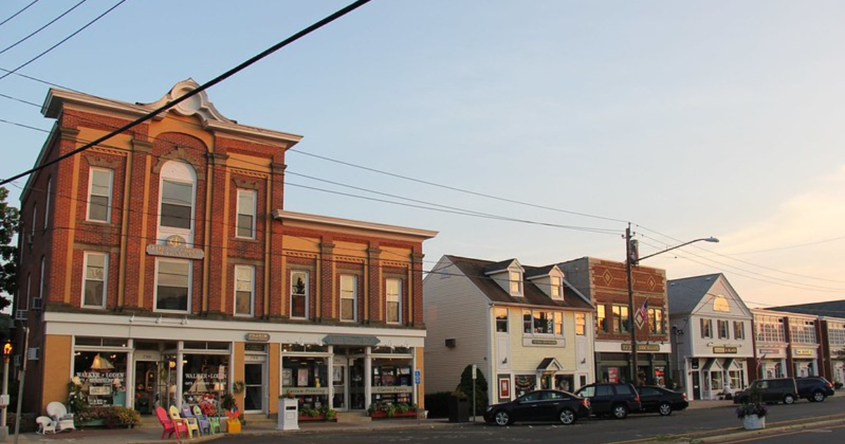 Boston Post Road in downtown Madison at golden hour, with a brick Victorian block and shopfronts.