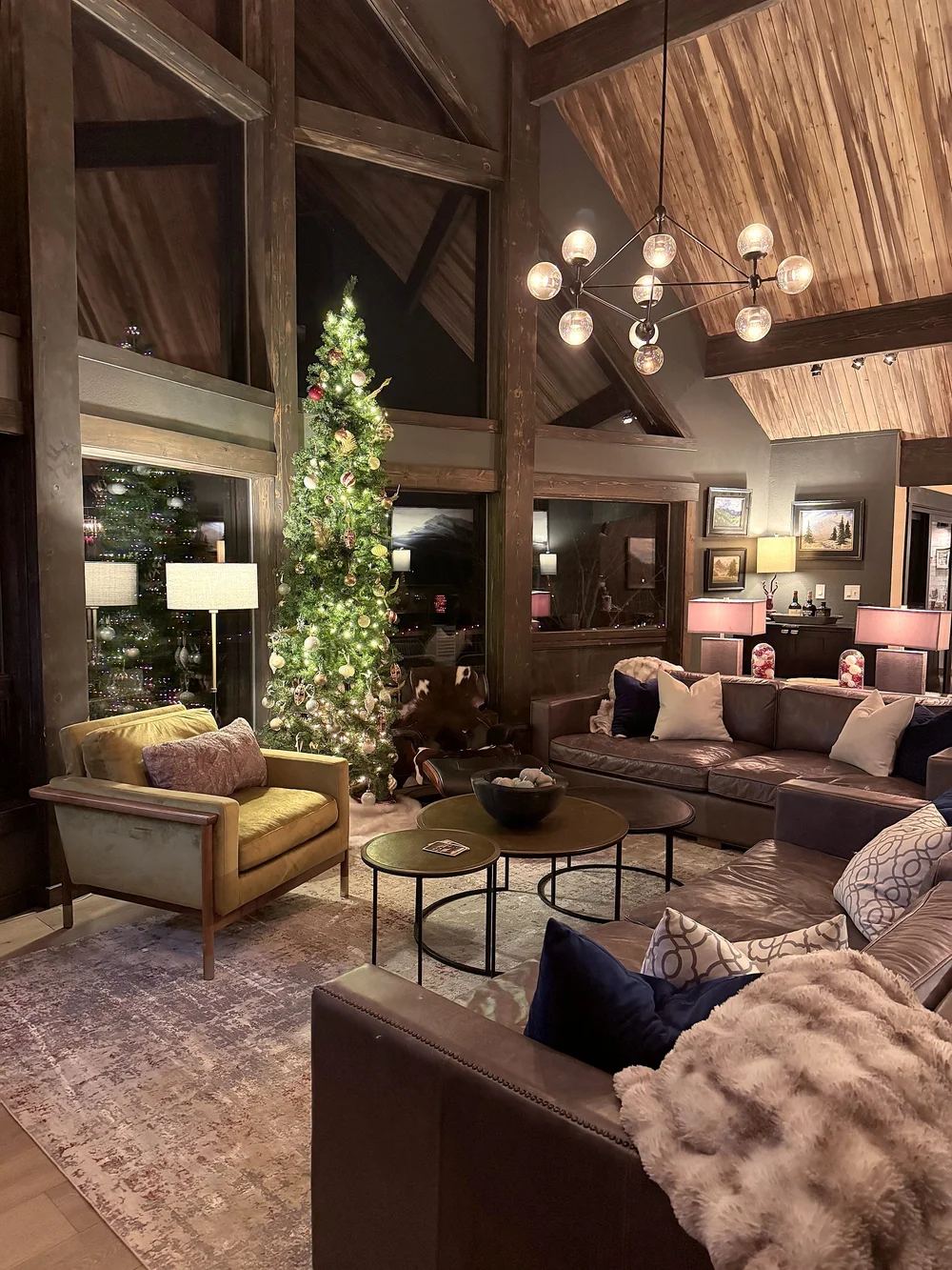 The great room at night with the Christmas tree lit and lamps glowing