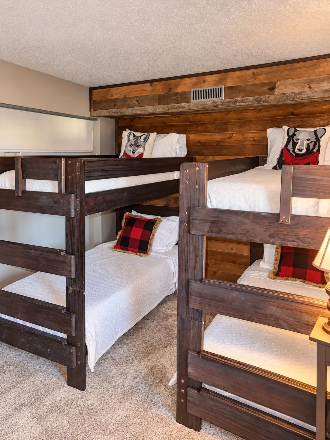 The bunk room with two sets of dark wood twin bunks against a reclaimed-wood wall