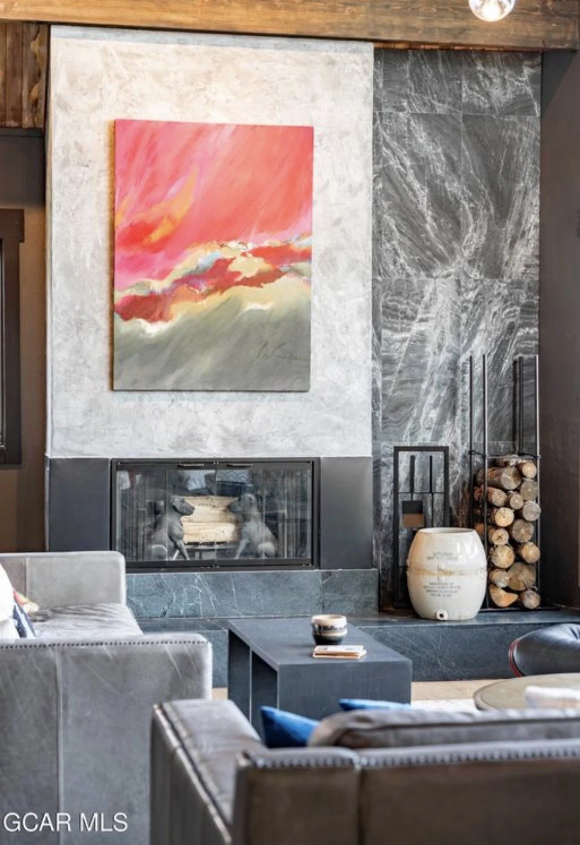 A pink and red abstract painting above the fireplace beside a wall of dark marble
