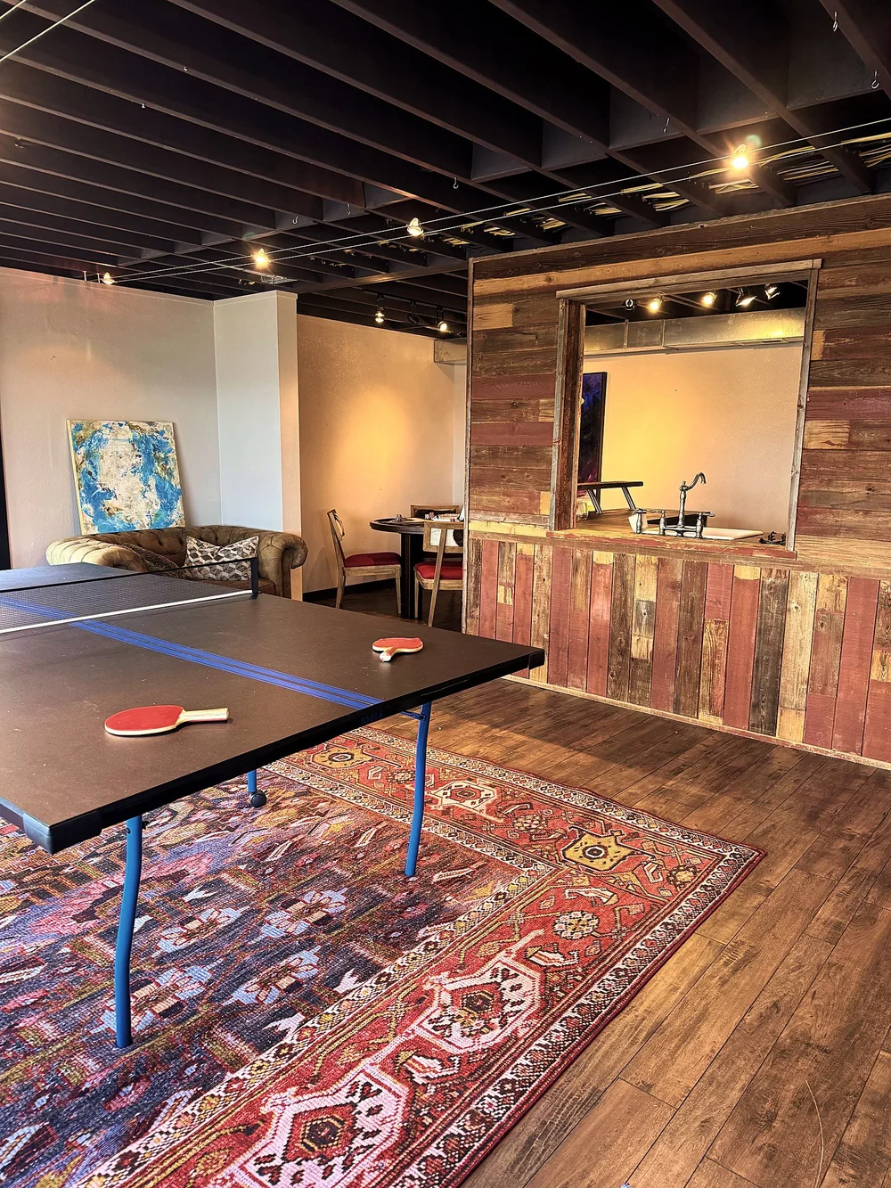 The ping pong table on a red rug in front of the reclaimed-wood bar