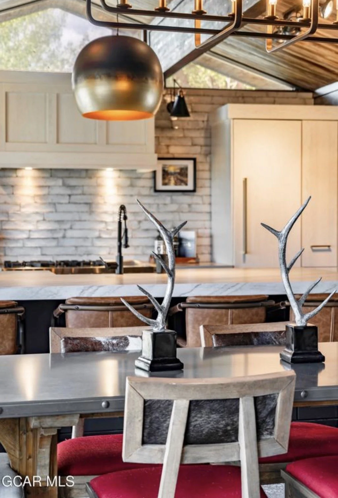 Silver antler sculptures on the dining table beneath a brass pendant light