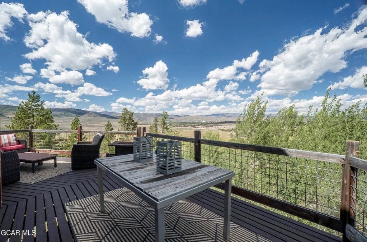 The deck with an outdoor table, lanterns and wide views across the valley to the mountains