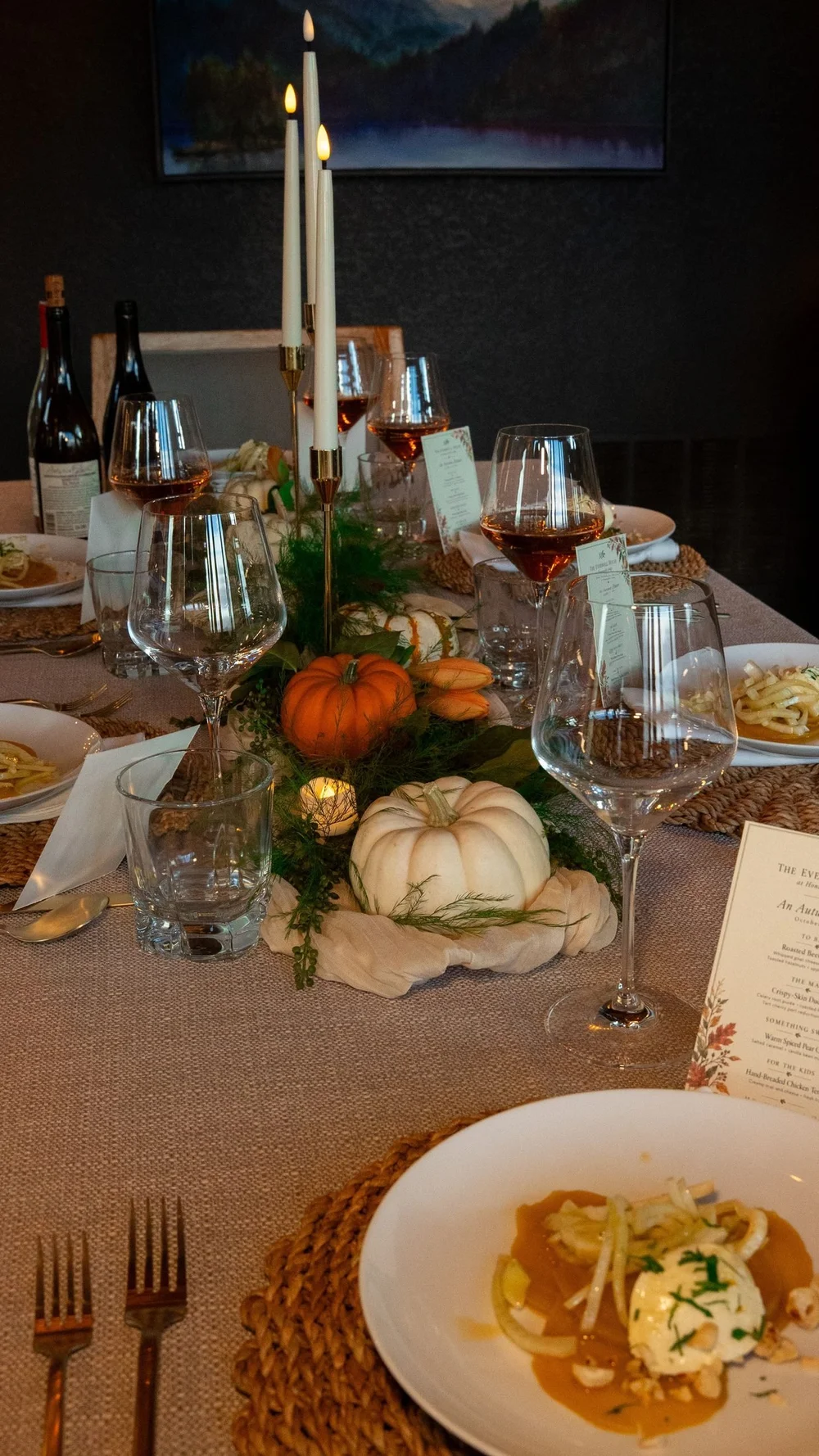 The dinner table set with candles, pumpkins, wine glasses and a printed menu