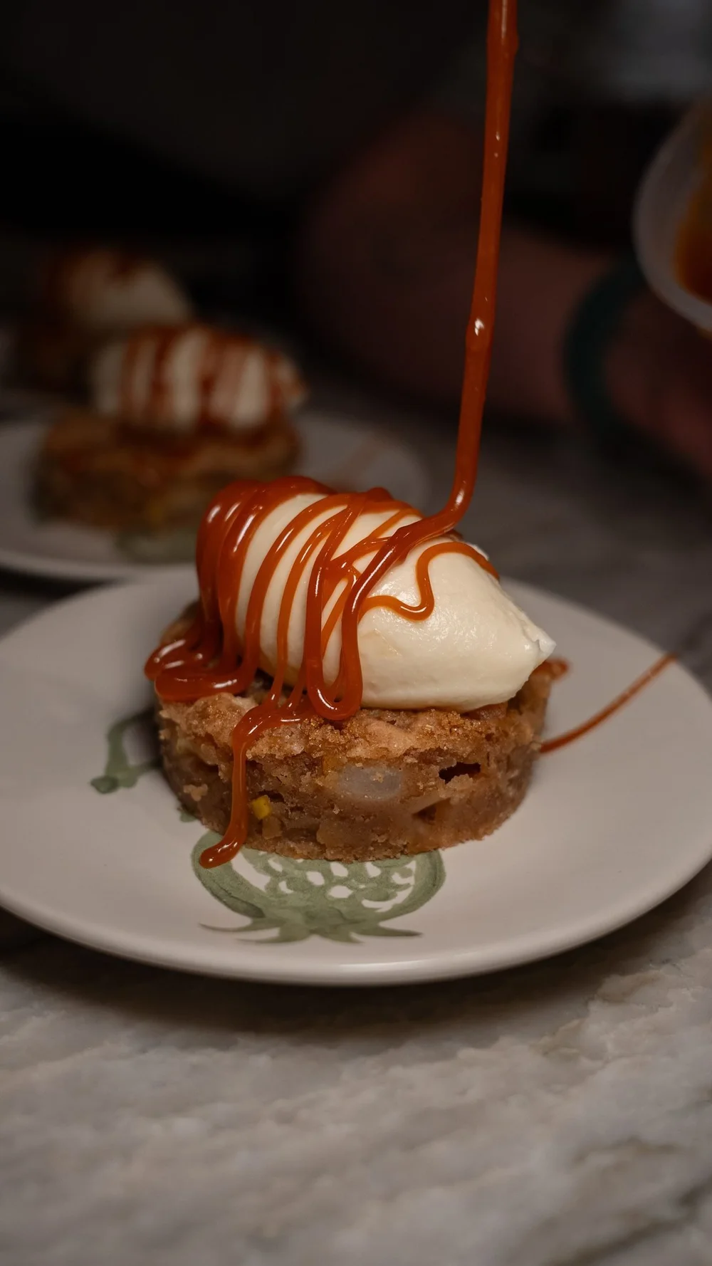 Caramel poured over a plated dessert with whipped cream