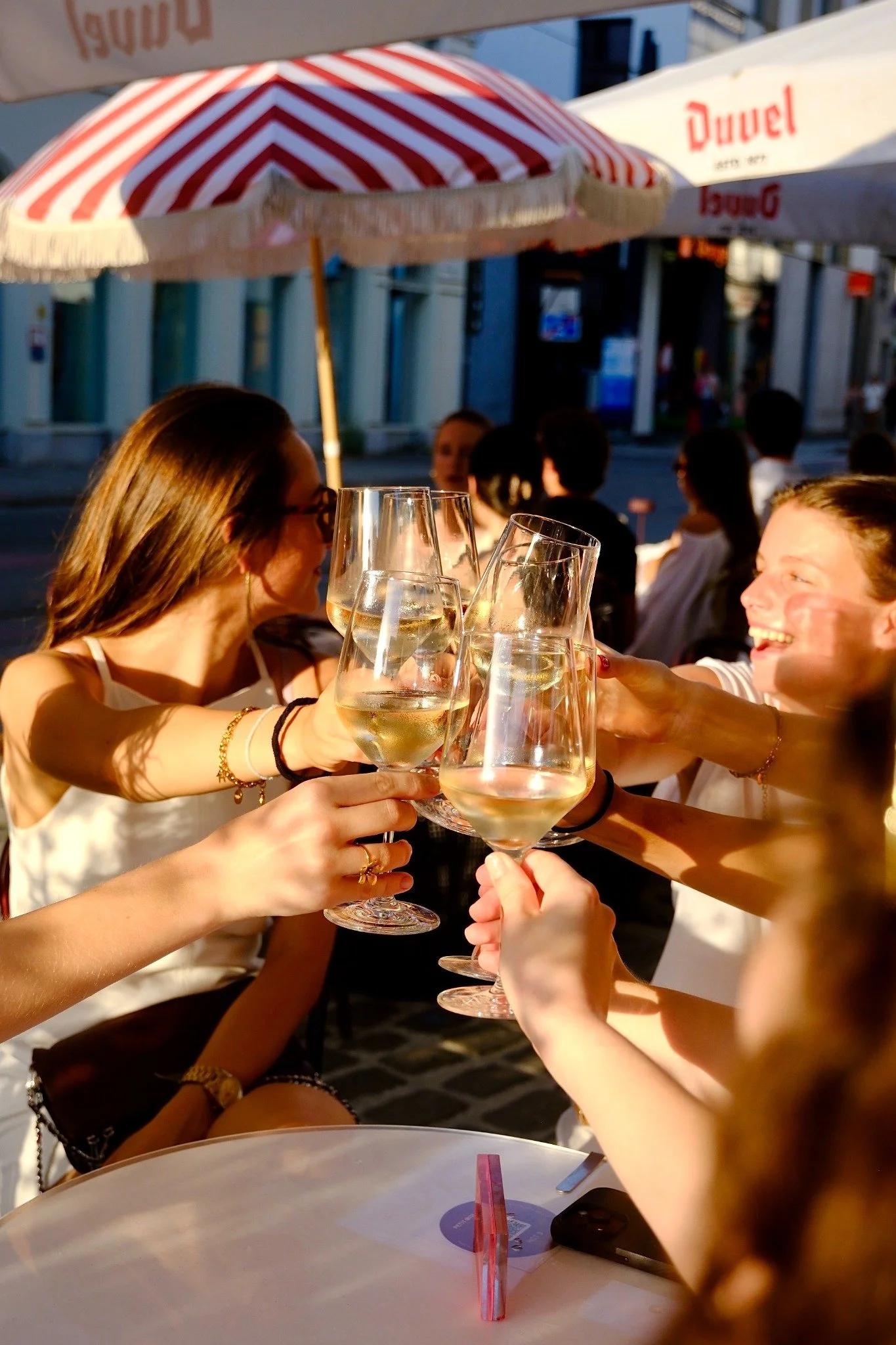 Vrienden klinken met hun glazen op het terras van Petit Midi