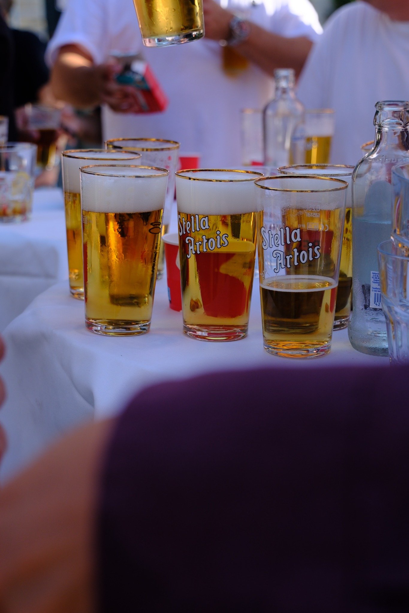 Glazen bier op tafel met gasten op de achtergrond bij Petit Midi