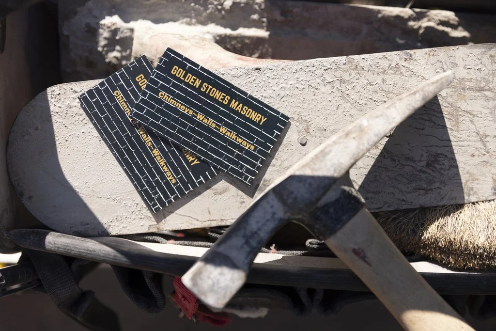 A Golden Stones mason grinding failed mortar out of the joints on a brick wall