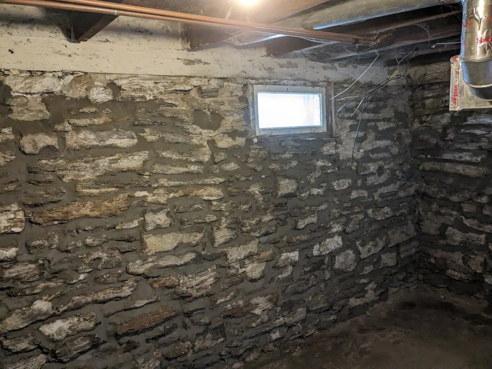 A Golden Stones mason grinding failed mortar out of the joints on a brick wall