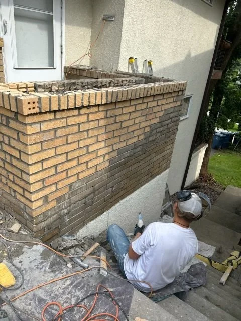 A Golden Stones mason repairing brickwork at ground level