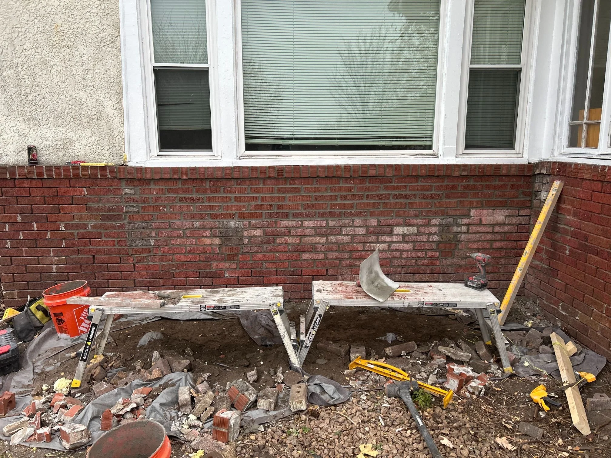 A brick wall partway through a partial rebuild with new ties