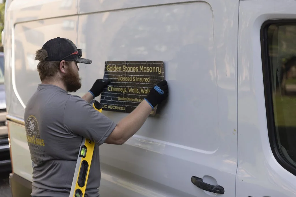 A Golden Stones mason fitting the company sign to the work van