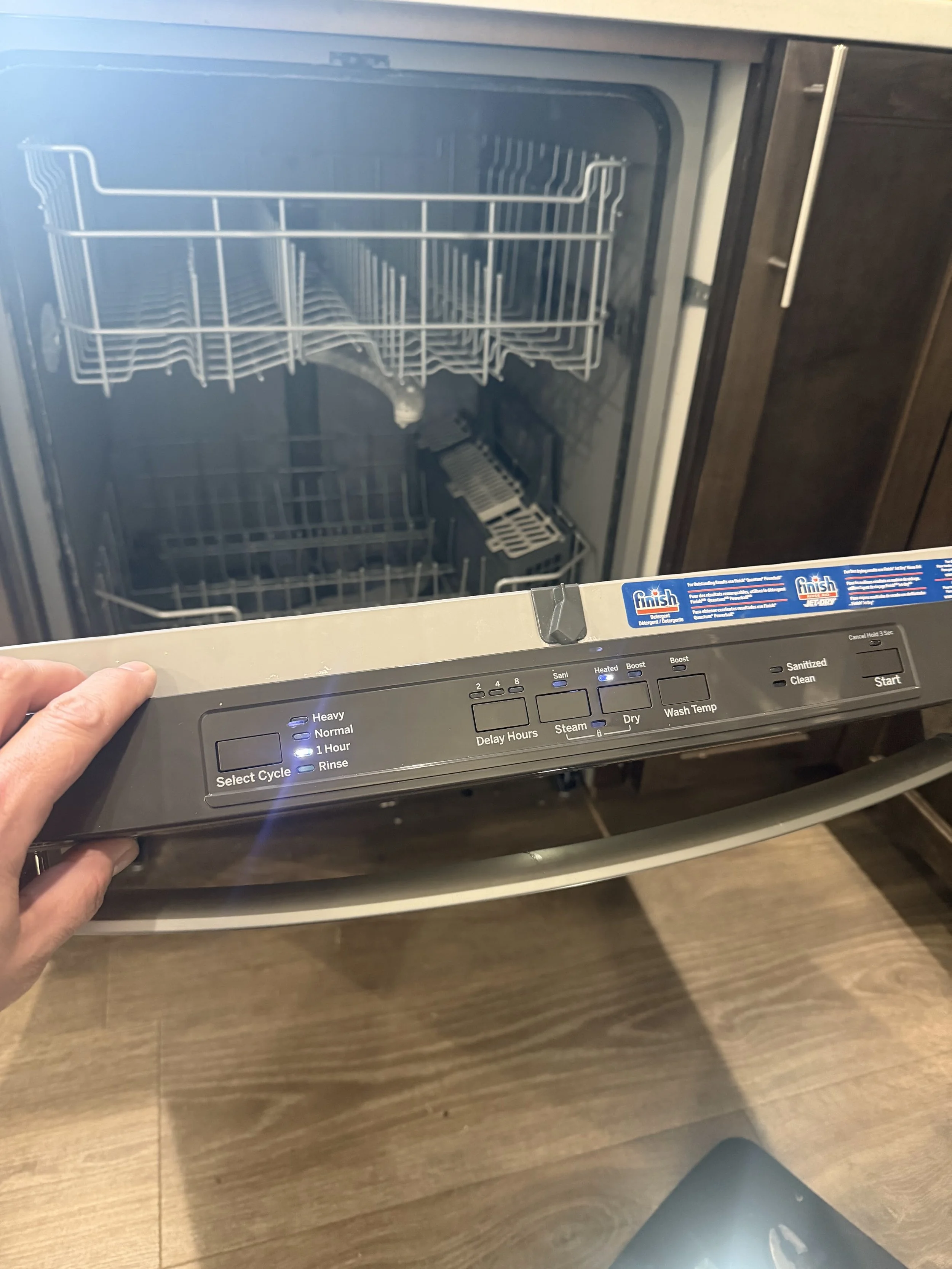 Dishwasher control panel with a finger on a button
