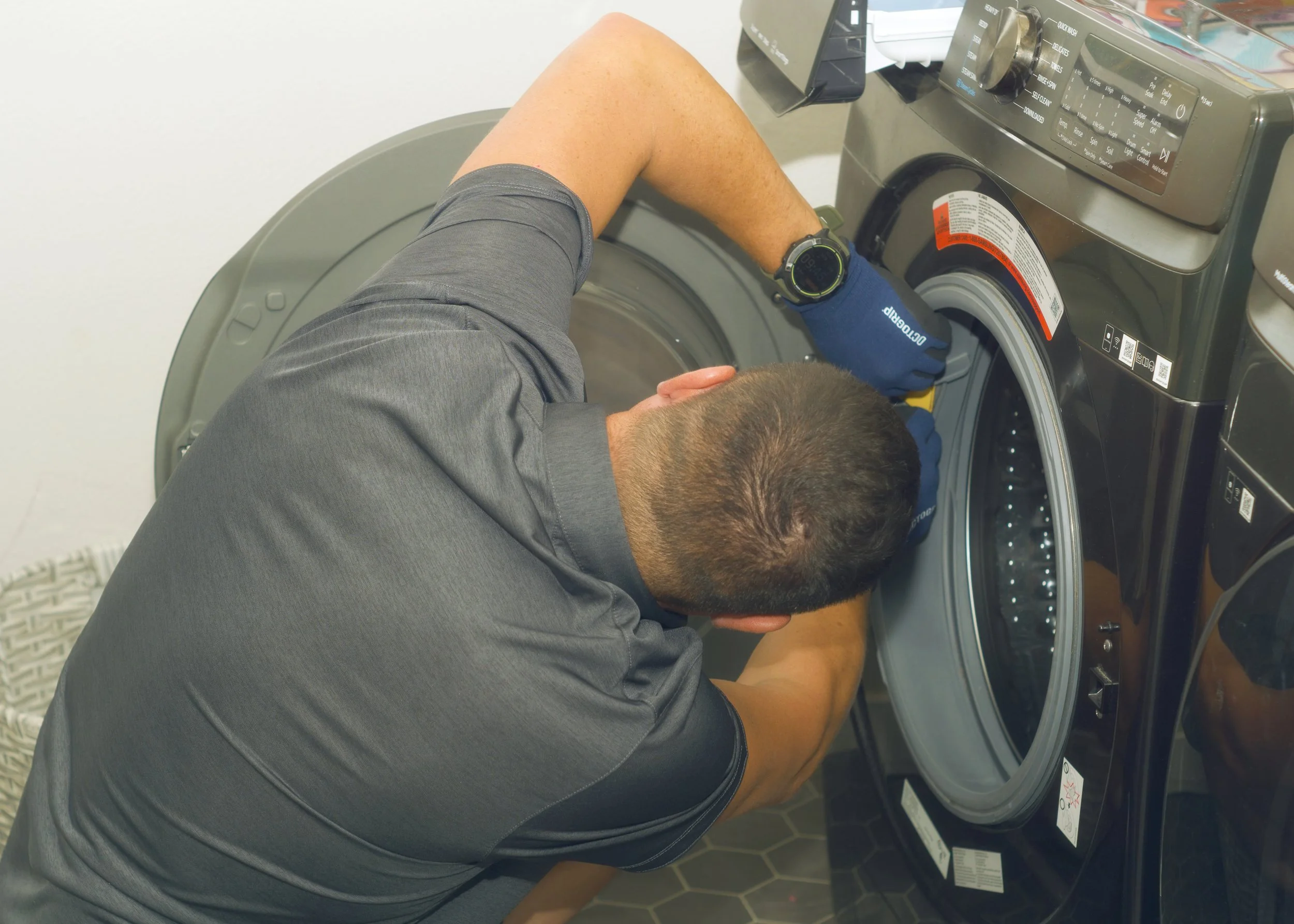 Technician working on a dryer drum, tracing a squeak or thump during a dryer repair in Post Falls