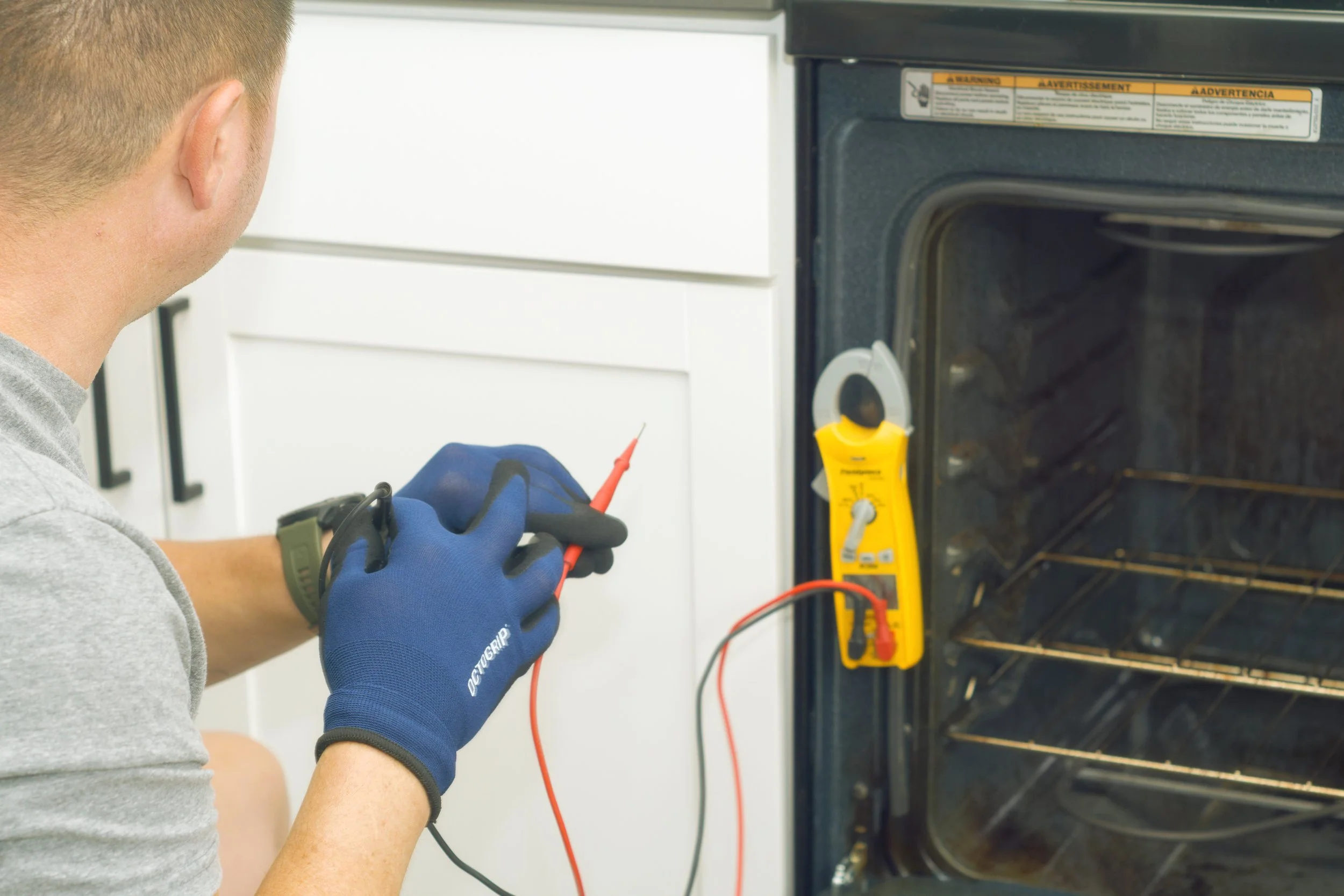Tech with a meter inside an oven during a Spokane appliance repair by SD Appliance