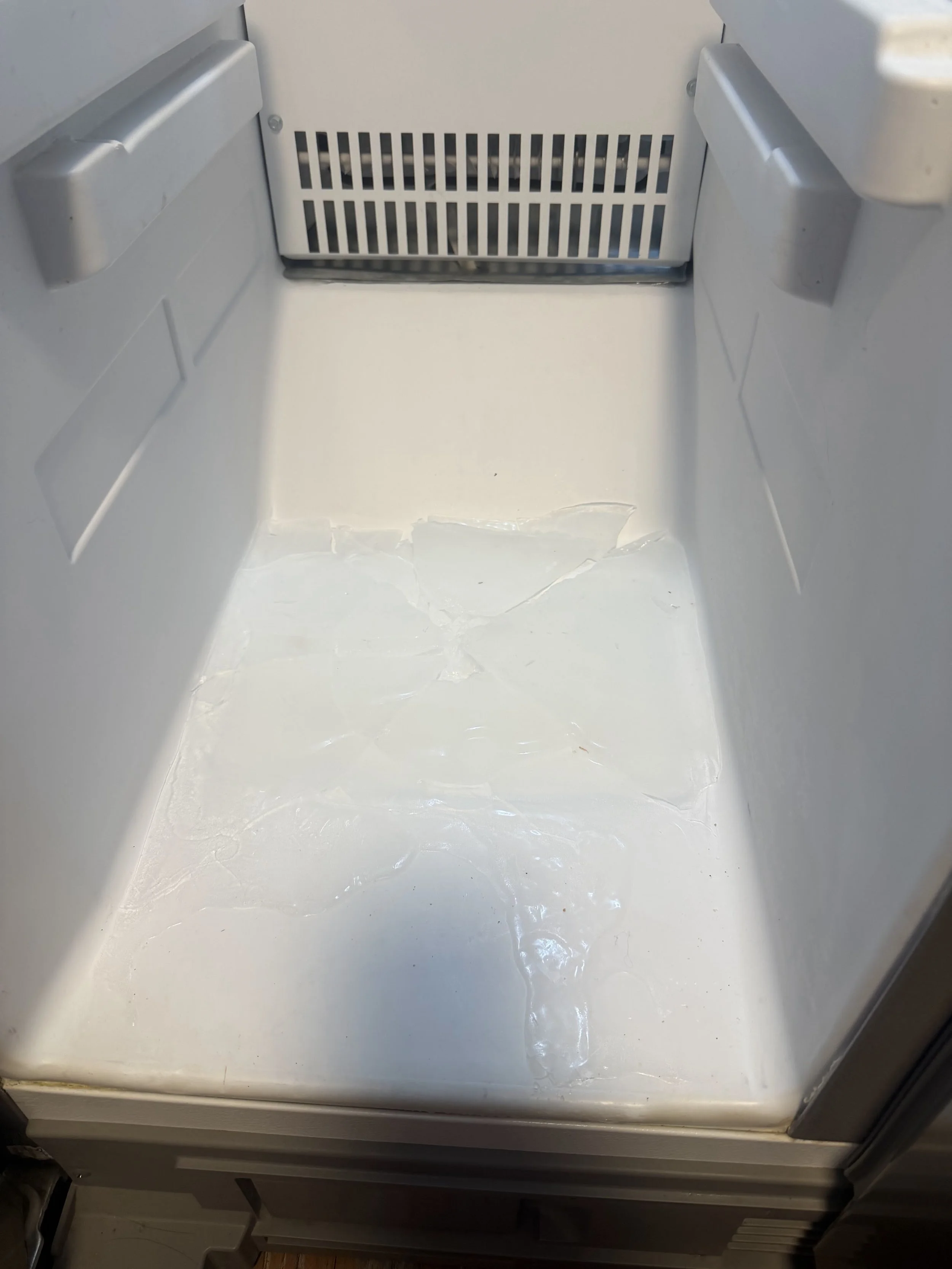 A sheet of frost and ice built up inside a freezer