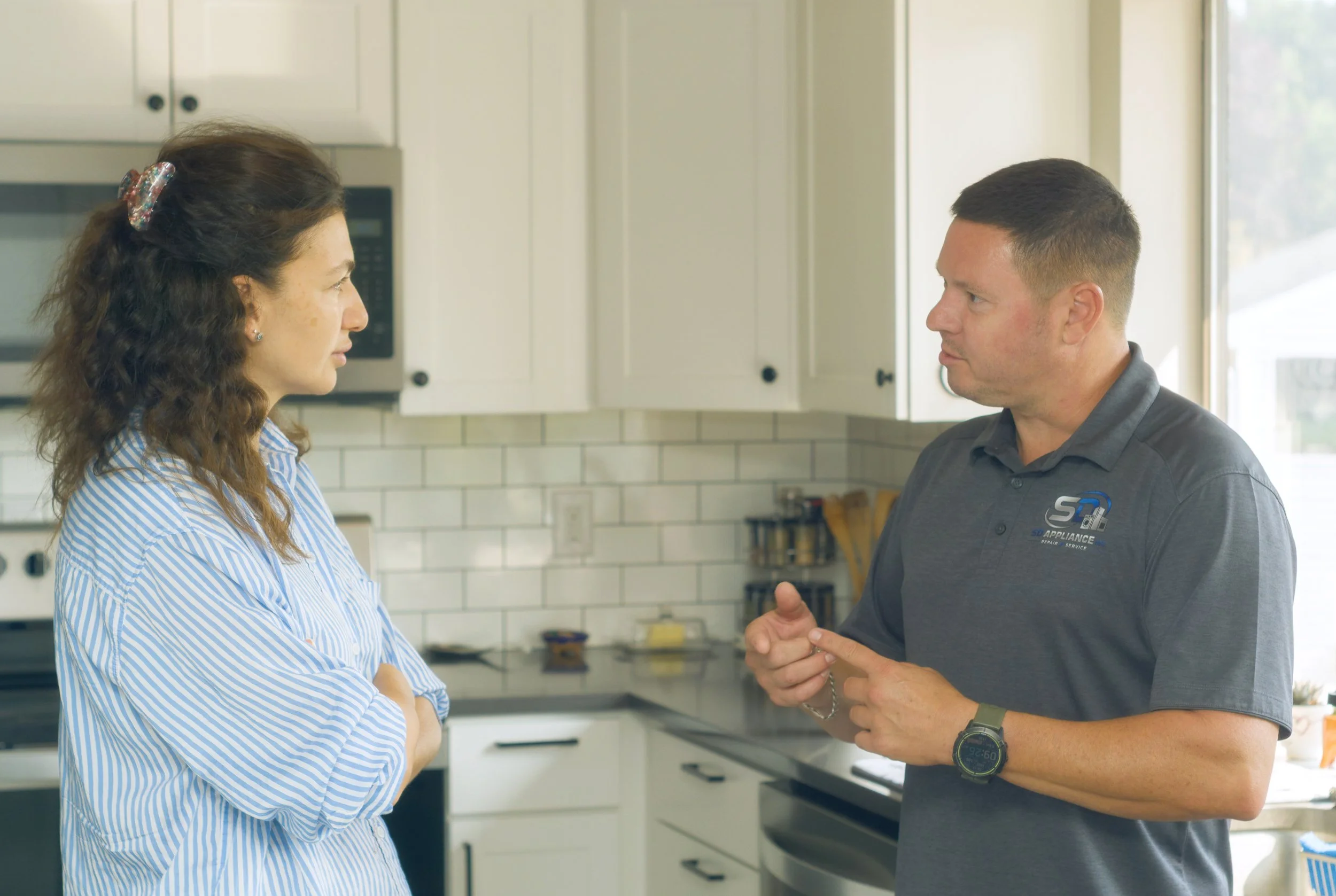 Sergei talking with a homeowner in her kitchen during a Spokane appliance repair by SD Appliance