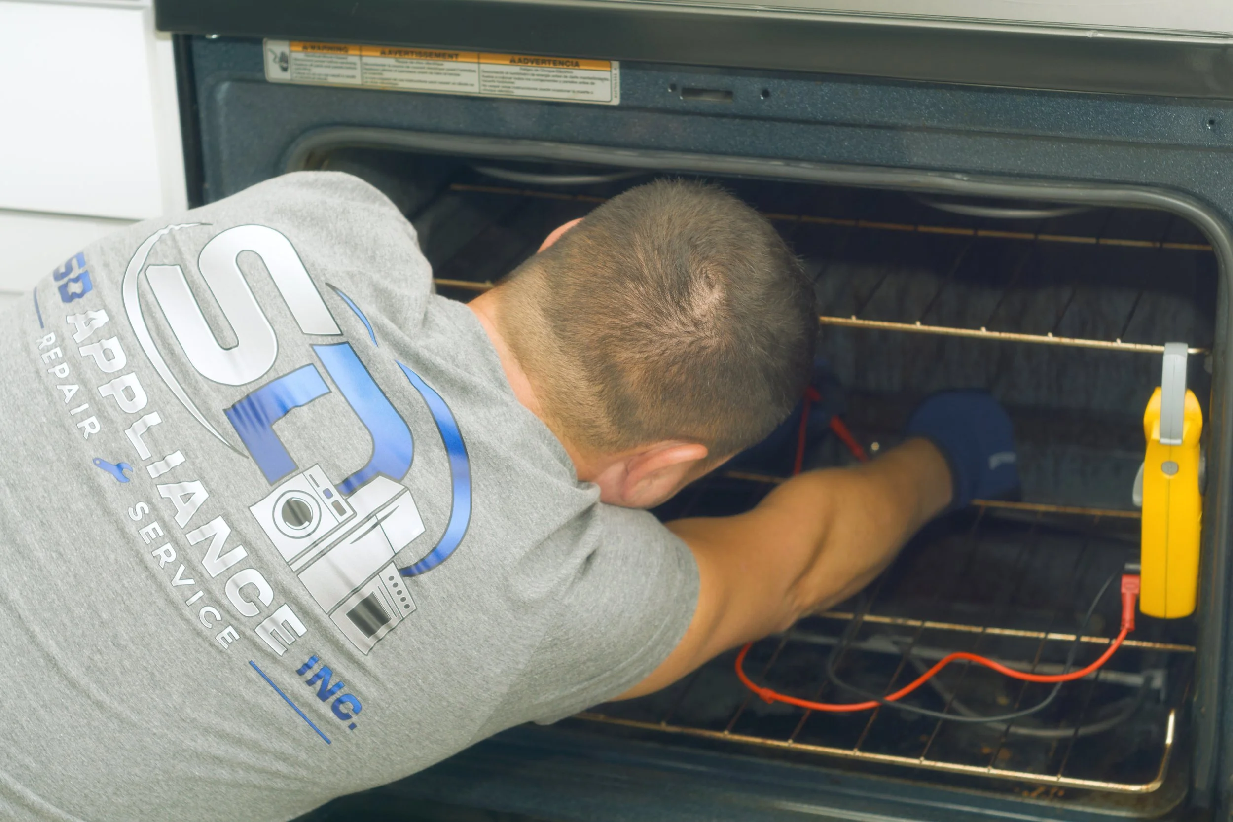 Sergei testing an oven element with a multimeter during an appliance repair in Spokane