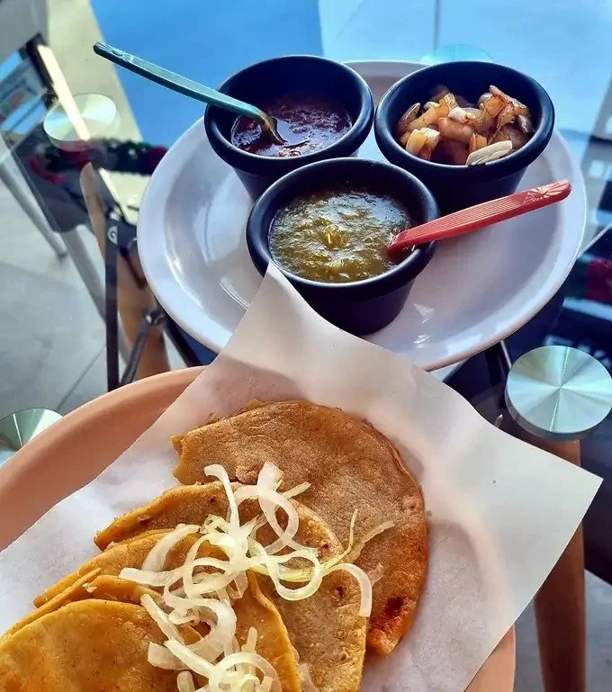 Orden de tacos de canasta Tacomible con salsa roja, salsa verde y cebollitas