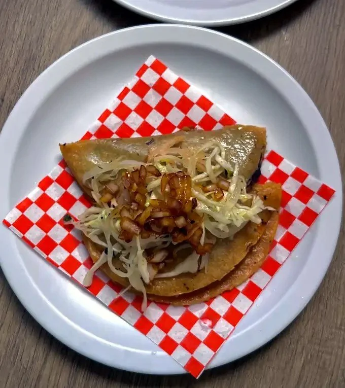 Taco de canasta Tacomible servido con col y cebolla asada