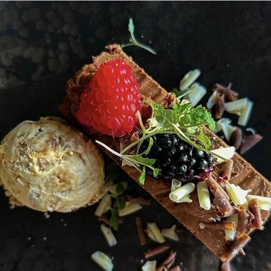 A chocolate torte dessert with fresh raspberries, blackberries and ice cream