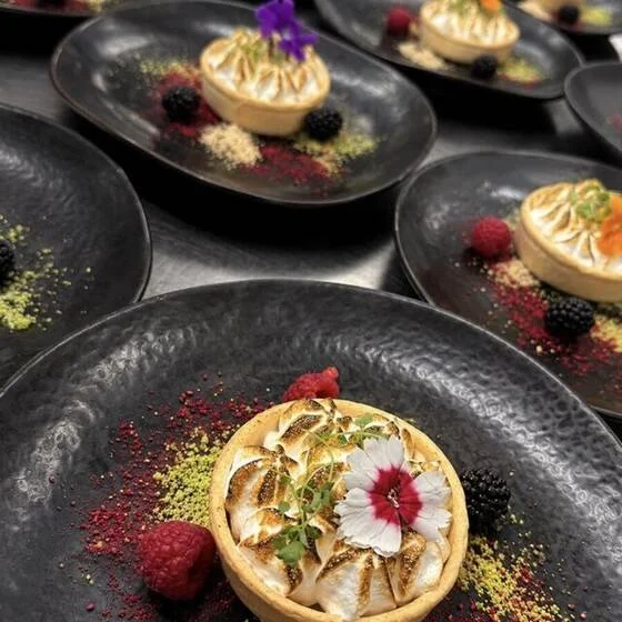 Lemon meringue tarts with berries on slate plates