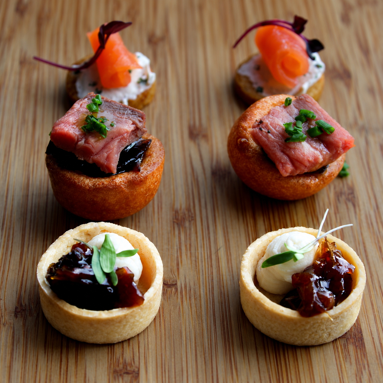 Yorkshire pudding canapés with rare beef, smoked salmon blinis and cream and chutney tartlets on a wooden board