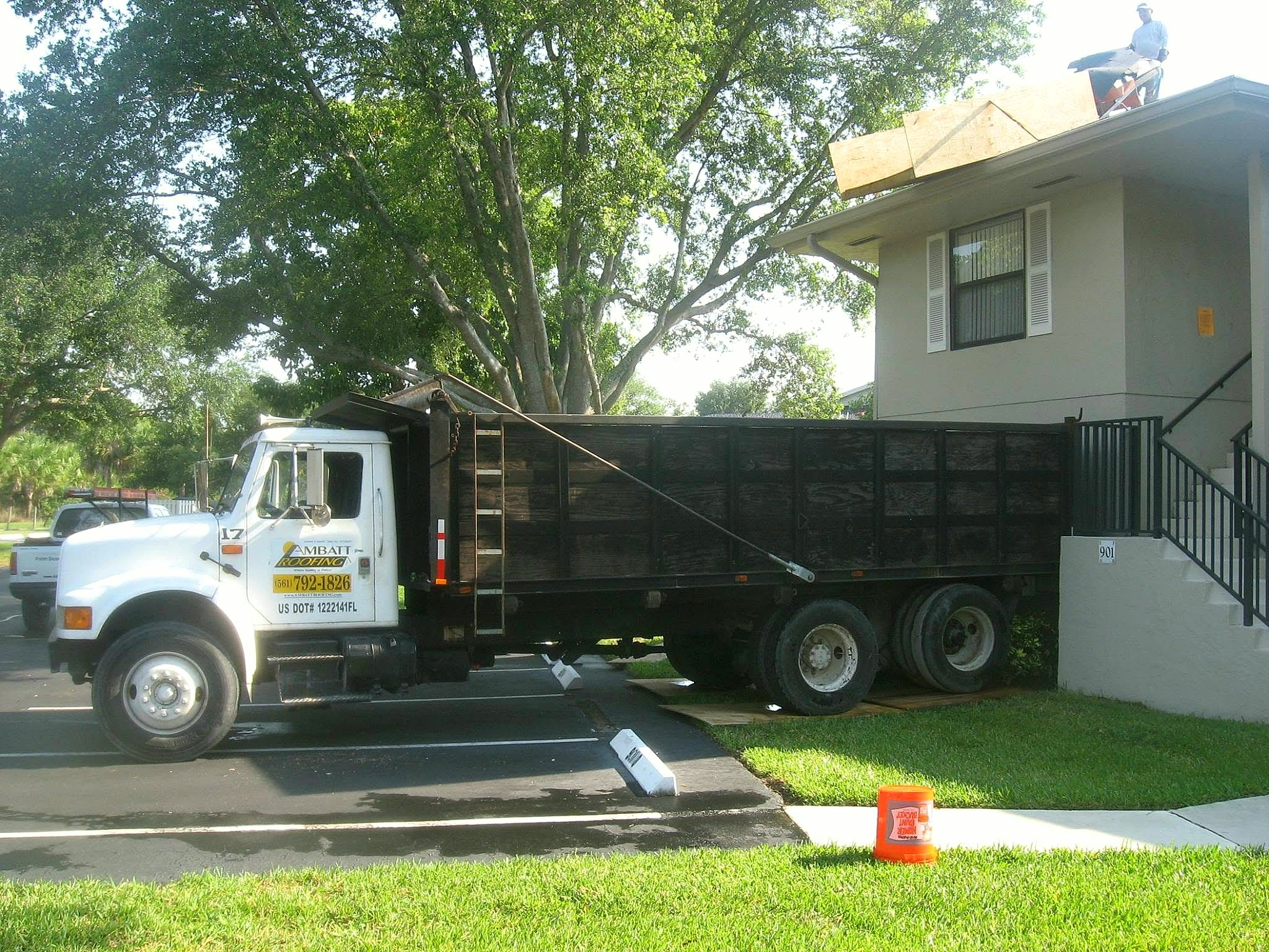Ambatt Roofing crew and dump truck on an active roof jobsite