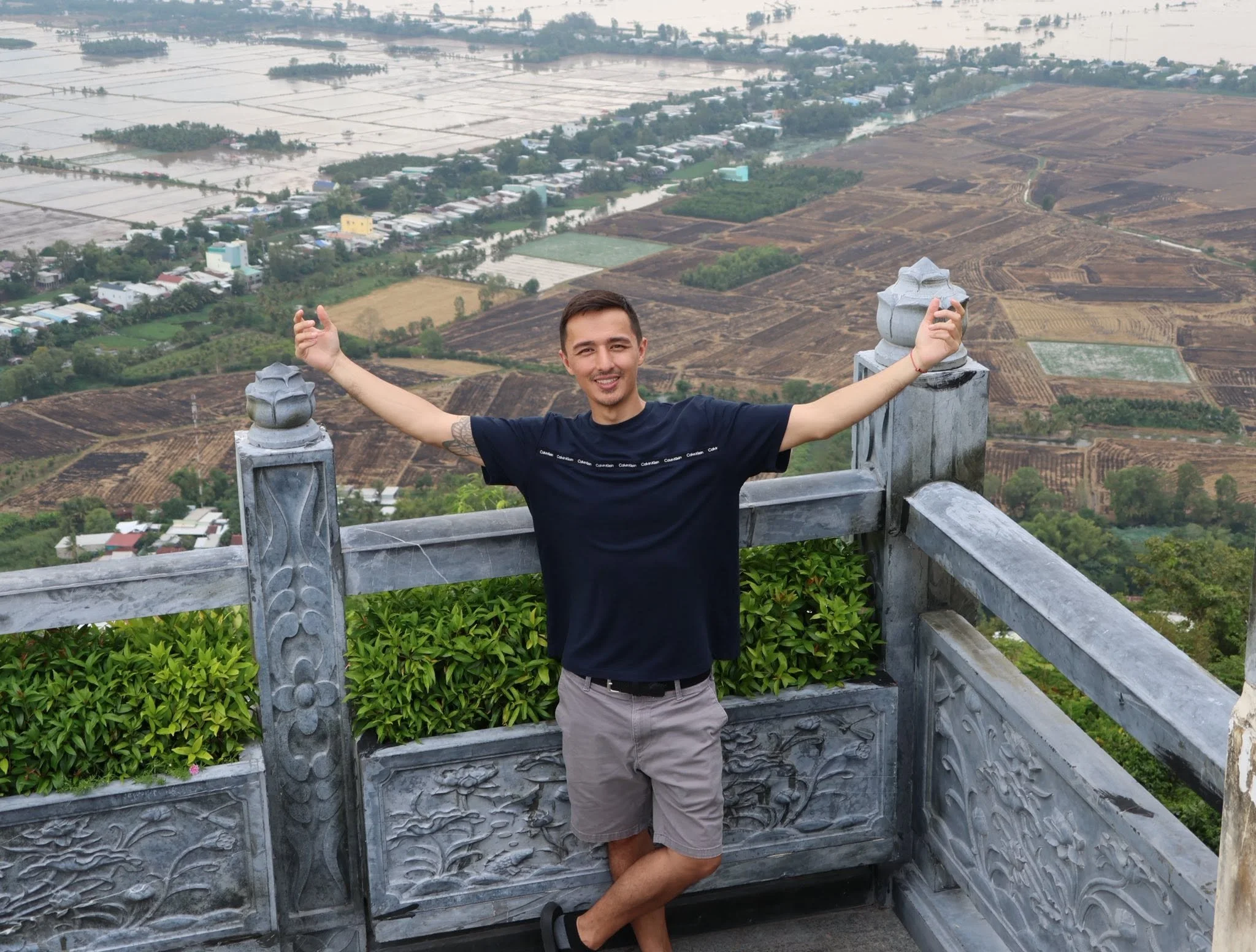 Tyler standing with his arms open at a scenic countryside overlook.