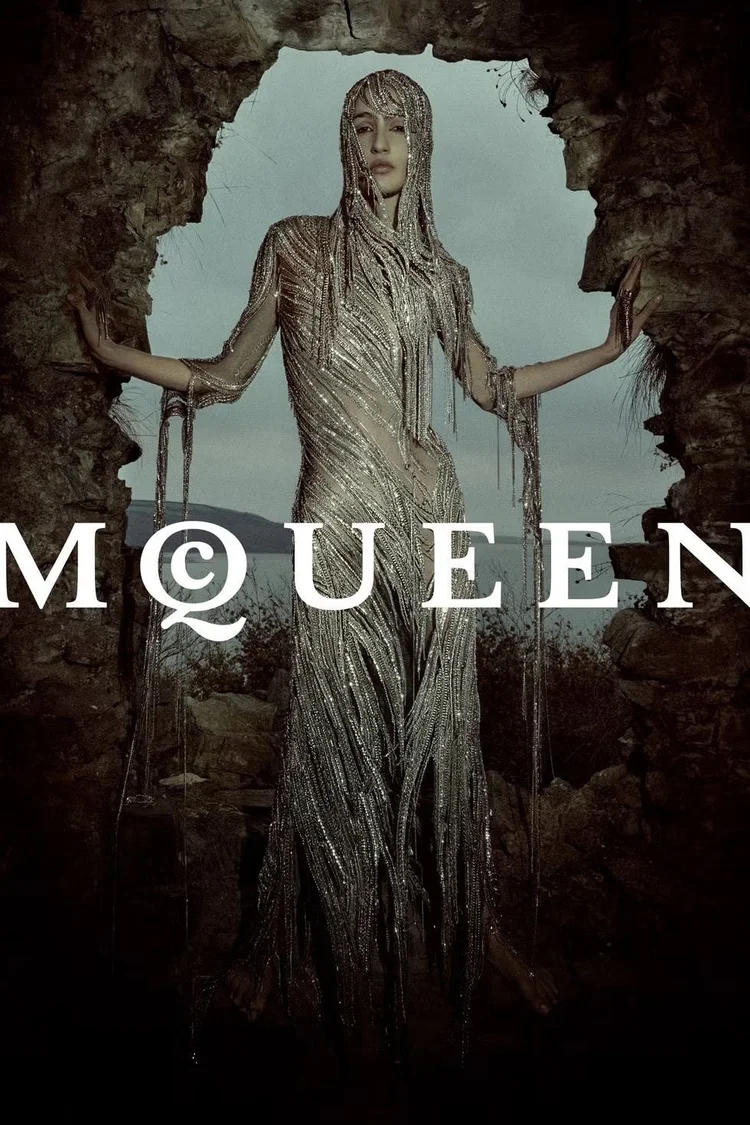 Beaded metallic hooded gown in a stone archway