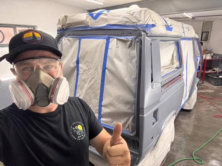 Person wearing a respirator beside a masked Volkswagen van