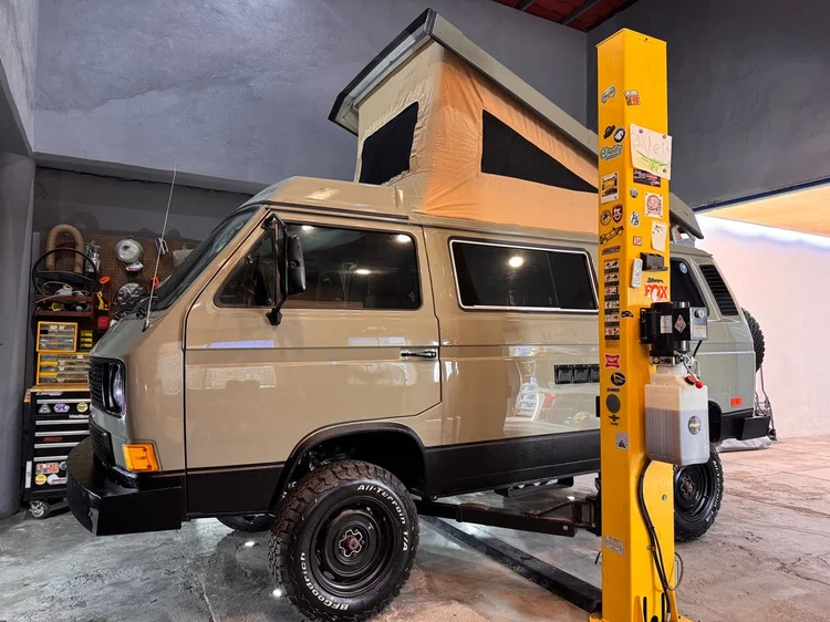 Brown Volkswagen Westfalia with raised pop-top inside the workshop