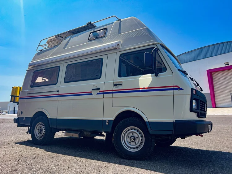 High-roof Volkswagen camper parked outside under a blue sky