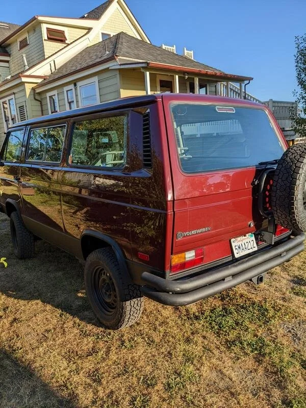 Rear view of a burgundy Volkswagen van parked on grass