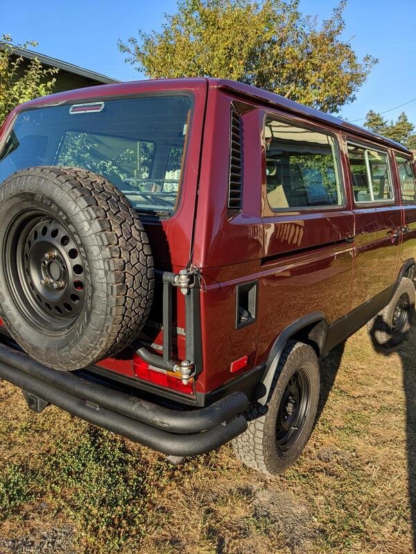 Rear quarter of a burgundy Volkswagen van with spare wheel carrier