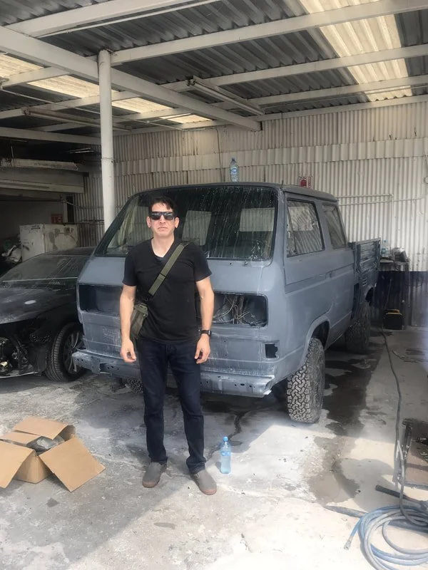 Person beside a Volkswagen double-cab pickup undergoing bodywork