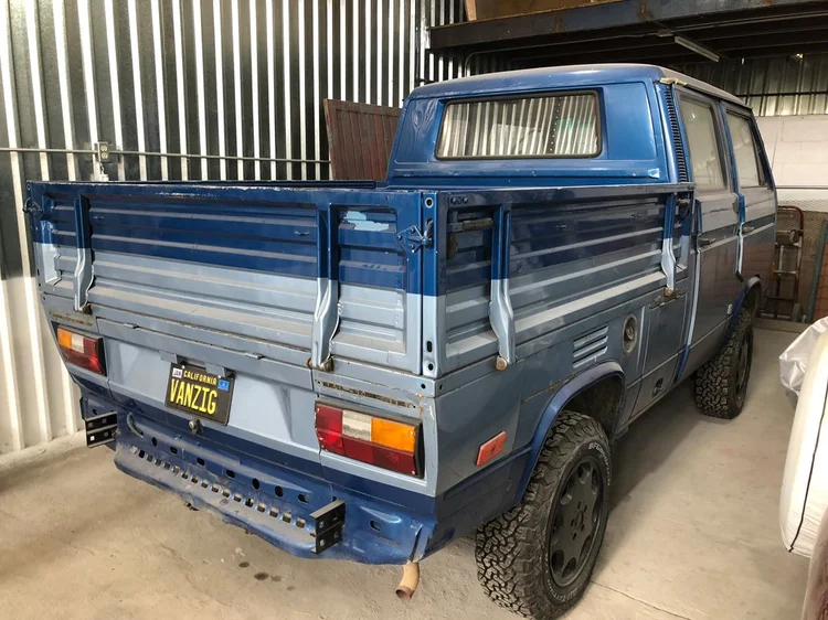 Rear view of a blue Volkswagen double-cab pickup inside the workshop