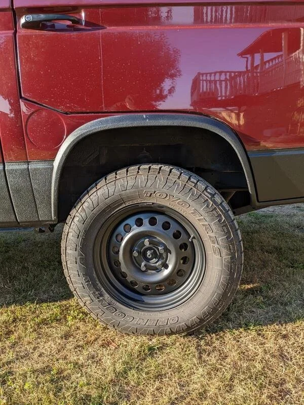 Rear wheel and wheel arch of a burgundy Volkswagen van